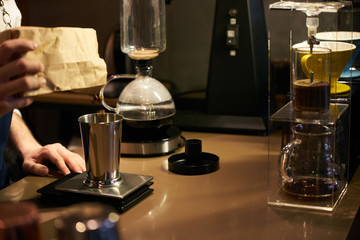 Barista weighs coffee on scales before preparing espresso. Professional barista equipment prepare for brewing drip coffee