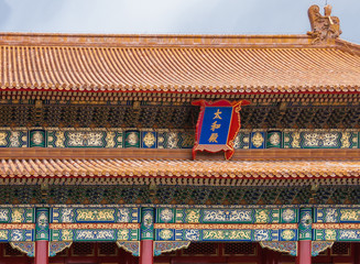 Beijing, China - April 27, 2010: Forbidden City. Closeup of highly decorated gold, orange and maroon roof structure against light blue sky. Traditional designs on beams.