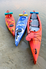 Three Traveling Kayaks on the Sand Beach near Beautiful River or Lake at the Evening. Travel and Adventure Concept.