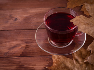 Autumn mood - Red tea and dry leaves on a wooden background