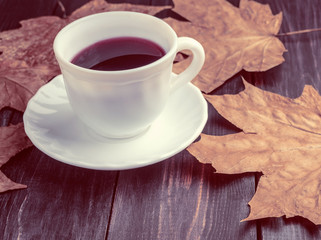 Coffee cup on the autumn fall leaves on wooden background
