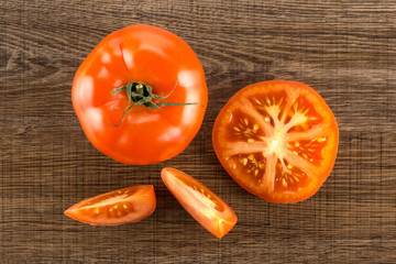 Red tomato collection top view isolated on brown wood background one whole one section half and two slices.