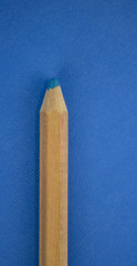 A sharp blue pencil sits on a bright blue background made of matching colors. Room for text on the right! 