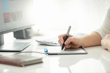 Fototapeta premium Closeup image of female graphic designer holding stylus and drawing on graphic tablet