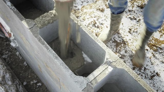 Workers work on building site, ground works. Detail of casting pump concrete to foundations of family house. Concrete pump, sky in background