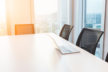 laptop on white desk in modern meeting room for present, large windows outside building, city, tower view, soft focus