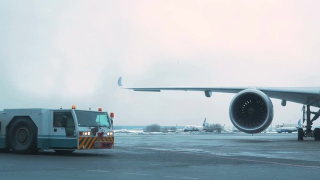 Airport Winter. Tow Tractor is near airliner. Cloudy Sky