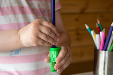child sharpens colored pencils