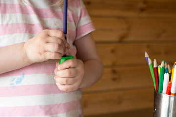 child sharpens colored pencils