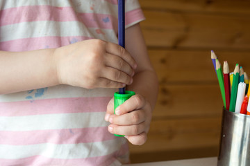 child sharpens colored pencils