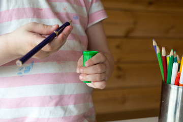 child sharpens colored pencils