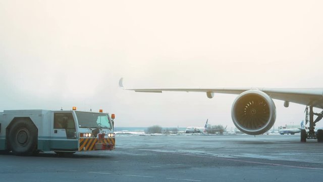 Airport Winter. Tow Tractor is near airliner. Cloudy Sky