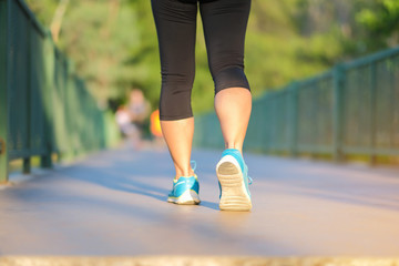 young fitness woman legs walking in the park outdoor, female runner running on the road outside, asian girl jogging and exercise on footpath in sunlight morning. healthcare and well being concepts