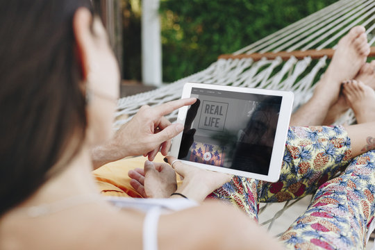 Couple using a tablet in a hammock