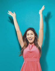 Happy young woman raising her arms on a solid background