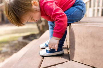 Happy toddler boy tying his sneakers outside