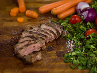 Juicy slices of grilled steak on wooden board
