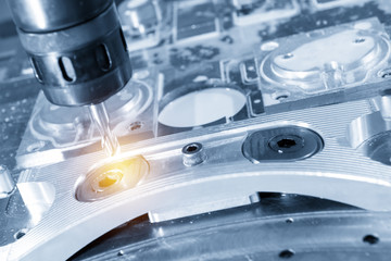 The CNC milling machine cutting the aluminium automotive part with the solid ball endmill in the light blue scene .Modern manufacturing process.