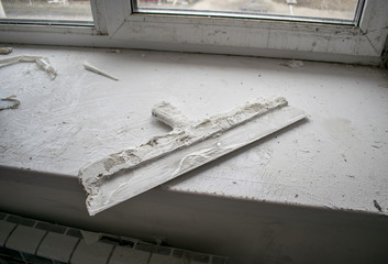 the building paint trowel in the plaster lies on the windowsill
