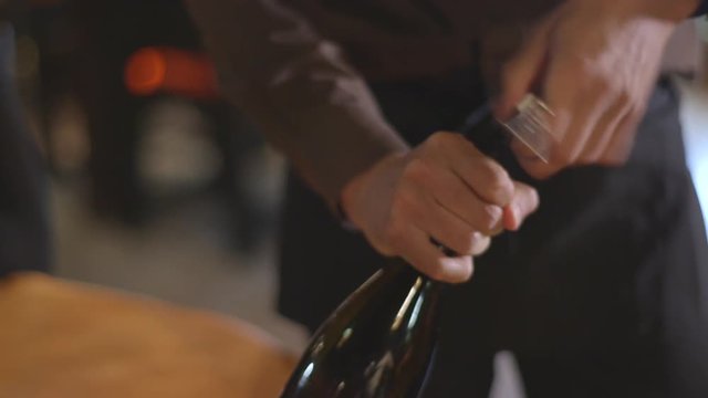 Close up, waiter opens wine bottle
