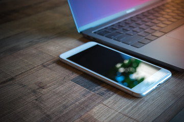 Computer Laptop and white mobile phone on wooden table background, blank screen electronic device with copy space - Powered by Adobe