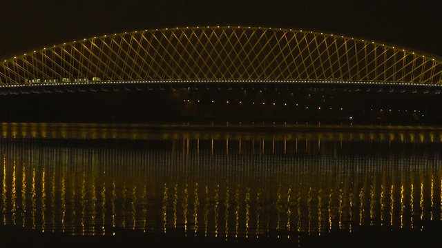 Tramway and cars cross the bridge at night traffic. Vltava river in Prague
