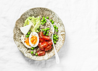 Morning savory breakfast bowl. Balanced bowl with quinoa, egg, avocado, tomato, green pea. Healthy diet food concept. Top view, on light background