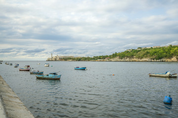 Fishing boats at the havana bay with the Morro lighthouse in the background. Havana Cuba.