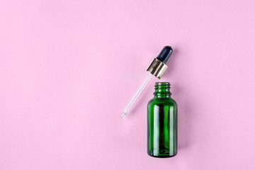 Minimalist photo of skin care, packaging for cosmetics. Green glass bottle with a pipette in pastel colors. Flat lay.