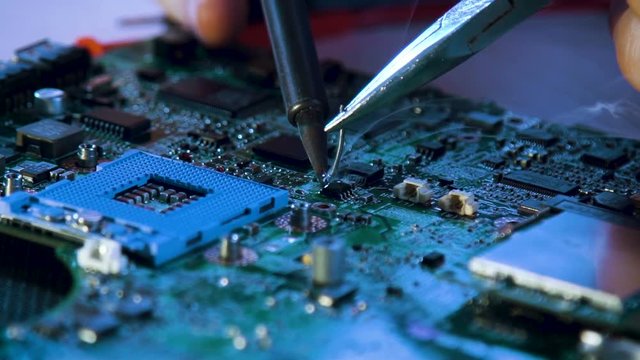 electronic renovation in repair shop. technician soldering motherboard