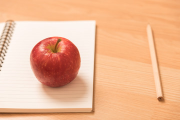 red apple on notebook with a pencil