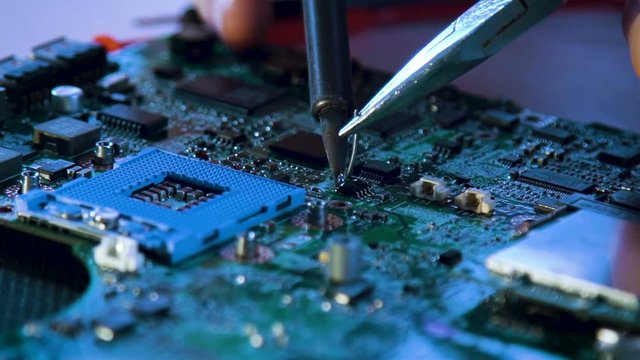 technology microelectronics science education. engineer student soldering computer motherboard
