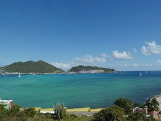 Fototapeta na wymiar Beatiful green and blue bay in Philipsburg, with a cruise ship docked at the port in the distance. 