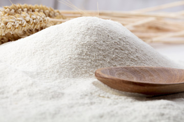 heap of wheat flour with wooden spoon and ears of wheat