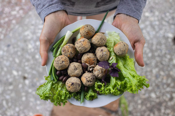 Woman hands holds vegan black beans falafel balls with salad leaves, basil, onion, tomato ketchup hot sauce served for lunch or dinner. Vegetarian healthy food