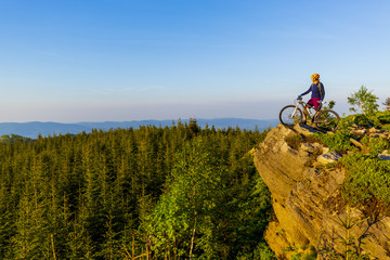 Fototapeta premium Mountain biking woman riding on bike in summer mountains forest landscape. Woman cycling MTB flow trail track. Outdoor sport activity.