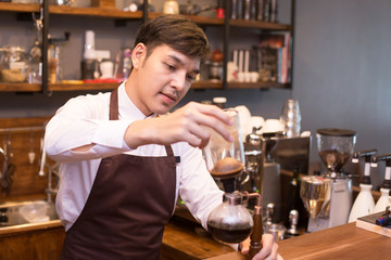 Asian male barista making coffee at coffee shop counter. Man with small business or sme concept.