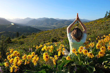 Woman meditating in medows with sunflowers Arnica. Seattle. Leavenworth. Washington State. United...
