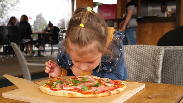 Hungry little girl - child funny stretch and eat mozzarella cheese from a pizza