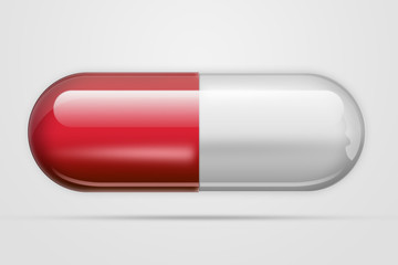 A pill in the form of capsules of red color, on a light background. The concept of medicine, treatment, treatment.