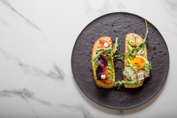 Toast with veggies,avocado, arugula, basil, tomato, mozzarella cheese  and sunny side up egg