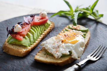 Toast with veggies,avocado, arugula, basil, tomato, mozzarella cheese  and sunny side up egg