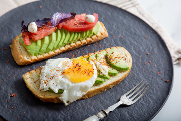 Toast with veggies,avocado, arugula, basil, tomato, mozzarella cheese  and sunny side up egg