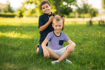 Two children are playing in the park. Two beautiful boys in T-shirts and shorts have fun smiling