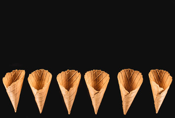 top view of row of appetizing ice cream cones isolated on black