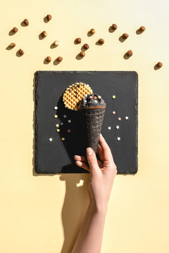 cropped image of woman holding black ice cream on yellow