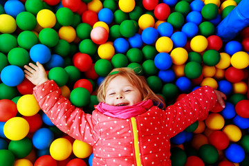 Fototapeta na wymiar little girl play in pool filled with colorful balls