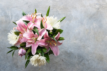 High angle view of flower bouquet with white chrysanthemums, pink lilies and purple rose over concrete background with copy space (selective focus)