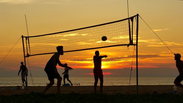 Travel Video group of silhouette people playing volleyball on the beach at sunset time in sport reaction concept.