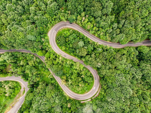 Winding curved road in the middle of the forest. Aerial shot using a drone